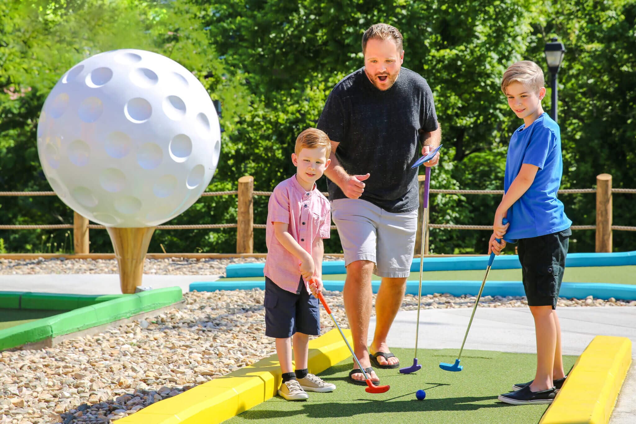 Family golfing next to a giant golf ball.